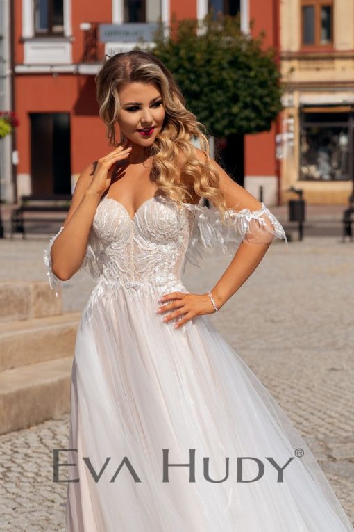 Lekka i subtelna suknia w delikatnym odcieniu nude z romantycznie opadającymi ramiączkami. Posiada pięknie wykończoną górę oraz zwiewny, tiulowy dół.