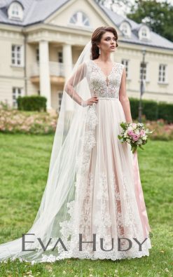 Subtelna suknia ślubna. Jej górna część, wykonana z wyrazistej koronki, jest dość zabudowana, co nadaje całości elegancji. Osadzona na grubych ramiączkach.