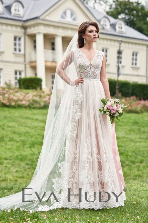 Subtelna suknia ślubna. Jej górna część, wykonana z wyrazistej koronki, jest dość zabudowana, co nadaje całości elegancji. Osadzona na grubych ramiączkach.