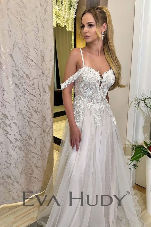 Romantyczna suknia ślubna o kroju litery A. Jej zwiewny dół idealnie współgra ze zdobną górą, a ich połączenie tworzy harmonijną i elegancką kompozycję. Dopełnieniem tej stylizacji jest zjawiskowy tren.