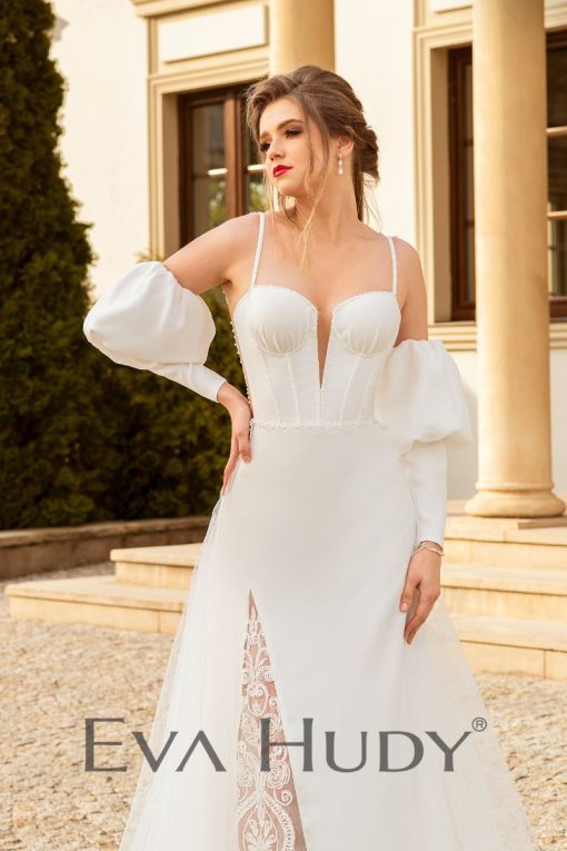 Subtelna suknia o niezwykle kobiecym charakterze. Góra sukni przyciąga uwagę swoją elegancją. Posiada rękawy dopasowane, zakończone subtelnymi bufkami.
